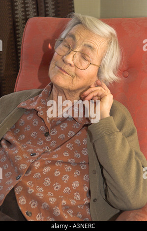 Donna anziana seduto nella sedia che sonnecchia Foto Stock