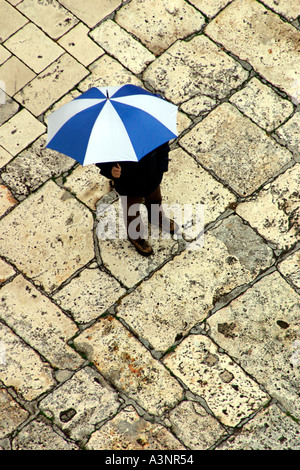Uomo in piedi con ombrellone sulla pavimentazione di pietra calcarea Vista aerea Foto Stock