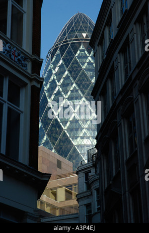 Il Gherkin Swiss Re Tower visto tra sopra e altri edifici di uffici nella città di Londra Foto Stock