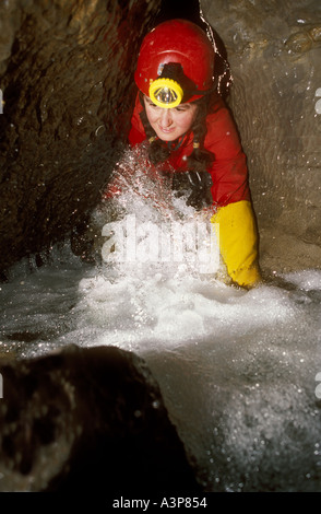 Speleologo strisciando in acqua in Galles del Sud grotta REGNO UNITO Foto Stock