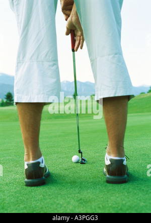 Il Golfer preparazione di swing, bassa sezione, vista posteriore Foto Stock