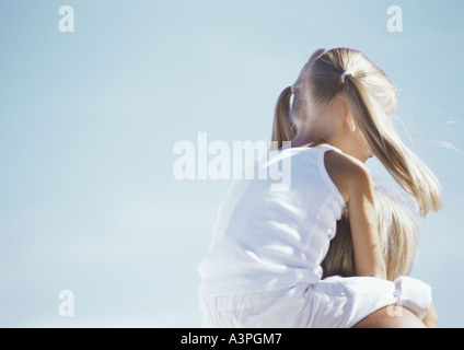 Bambina equitazione sulla madre di spalle Foto Stock