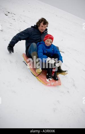 Scene di neve aberystwyth ceredigion 8 feb 2007 padre e figlio sulla slitta a giocare nella neve Foto Stock