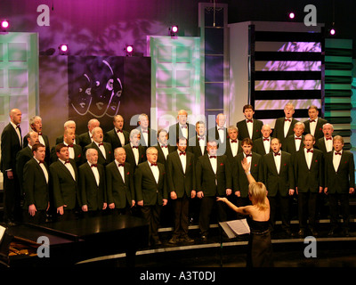 Donna conducendo un tradizionale gallese voce maschile coro cantando in concorso per il miglior coro in Galles Foto Stock