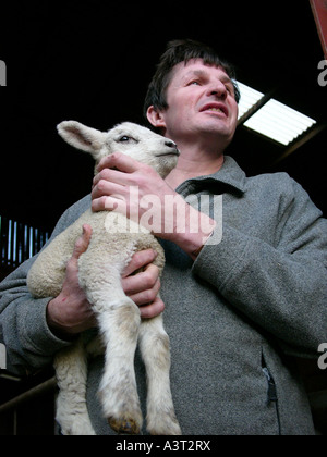 Welsh farmer holding agnello neonato in agriturismo vicino a Aberystwyth Ceredigion REGNO UNITO GALLES Foto Stock