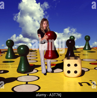 Donna su un enorme parco giochi con una pedina in mano Foto Stock