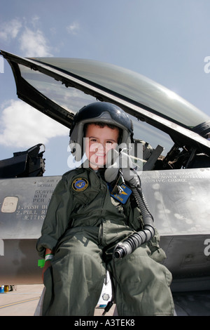 Piccolo Ragazzo vestito di pilota tuta s seduto accanto al cockpit di un F16 Foto Stock