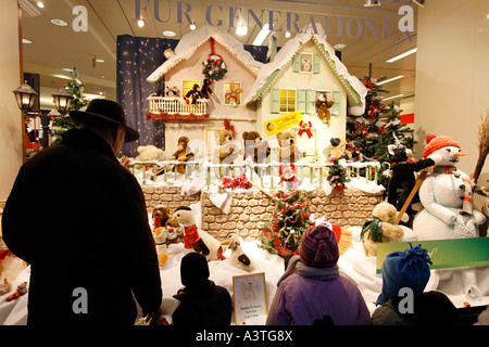 Padre e figli guardare una finestra di natale in un grande magazzino decorate con giocattoli di peluche, Duesseldorf, NRW, Germania Foto Stock