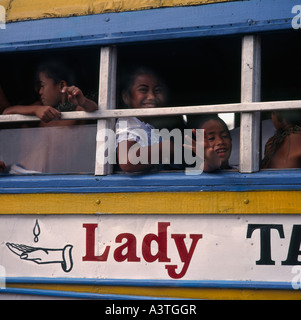 Stile locale Chiesa di Samoa bus in giallo colorato di bianco e blu con le ragazze in corrispondenza della finestra di Apia città sull Isola Upolu Samoa occidentale Foto Stock