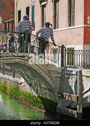 Due gondolieri in piedi su un piccolo ponte su un canale di Venezia Veneto Italia UE Foto Stock