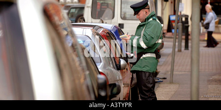 Un vigile mani un biglietti per il parcheggio su una strada trafficata in Brighton. Foto Stock