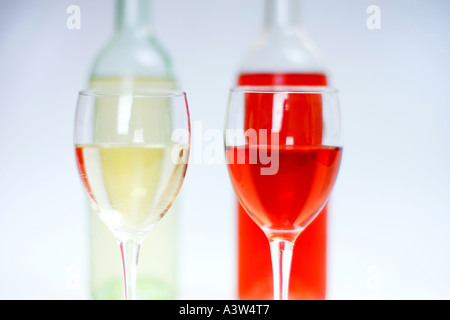 2 bicchieri di bianco e vino rosato con bottiglie dietro e bianco sfondo isolato Foto Stock