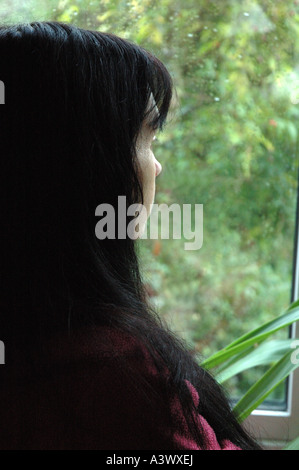 La donna a guardare fuori di una pioggia finestra schizzato in inverno Foto Stock