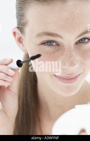 Una giovane donna applicazione di mascara Foto Stock