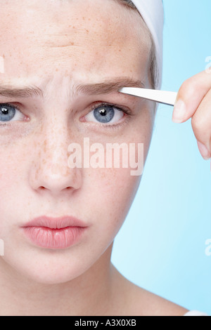 Una giovane donna spiumatura sopracciglia close up Foto Stock