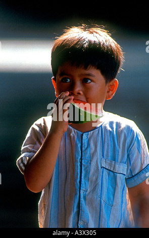 Ragazzo mangia la fetta di cocomero Thailandia Foto Stock