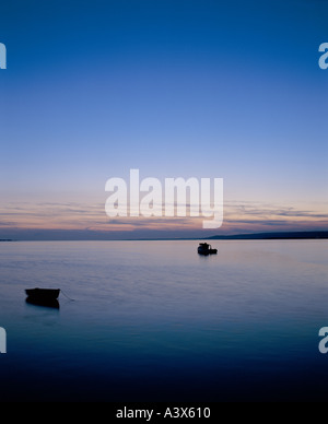 Due barche all'ancora nella baia di Swansea al tramonto del Galles. Con bellissimi colori nel cielo riflessi nel mare vonghè Foto Stock