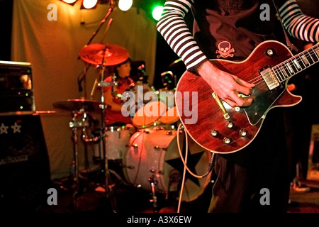 Close up del Rock and Roll chitarrista sul palco con il batterista in background. Foto Stock