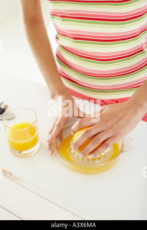 La donna la spremitura di un arancione con una centrifuga Foto Stock