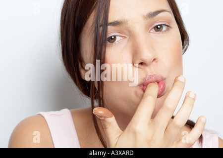 Una giovane donna leccare il cioccolato dalla sua dita Foto Stock