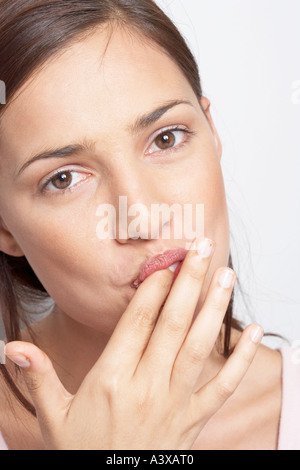 Una giovane donna leccare il cioccolato dalla sua dita Foto Stock