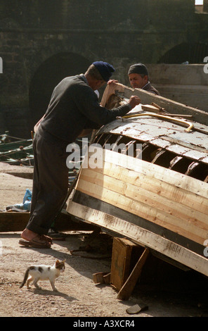 I pescatori rammendo una barca nel porto di Essaouira, Marocco Foto Stock