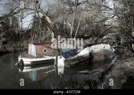 Un rovesciamento cruiser barca a fianco di un narrowboat abbandonati sulla Oxford Canal Foto Stock