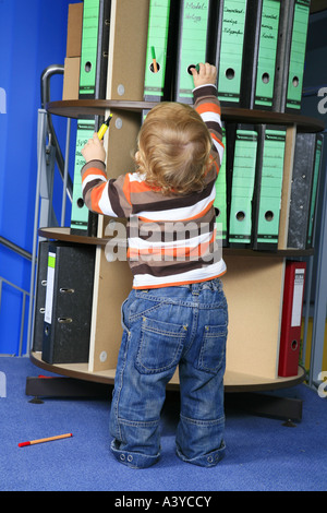 Piccolo Ragazzo davanti a una cartella rack di stoccaggio in ufficio Foto Stock