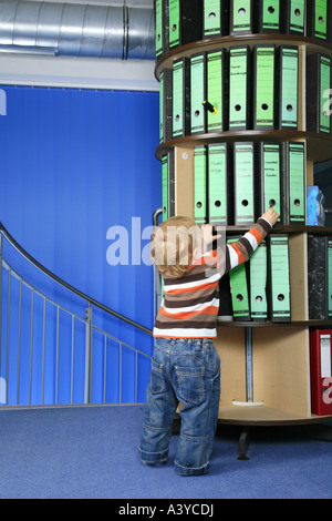 Piccolo Ragazzo davanti a una cartella rack di stoccaggio in ufficio Foto Stock