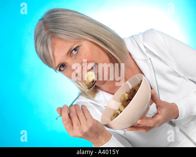 Donna matura mangiare cereali con banana modello rilasciato Foto Stock