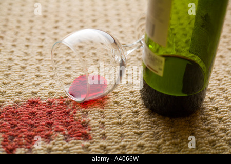 Ribaltato un bicchiere di vino rosso con vino versato su un tappeto di lana Foto Stock