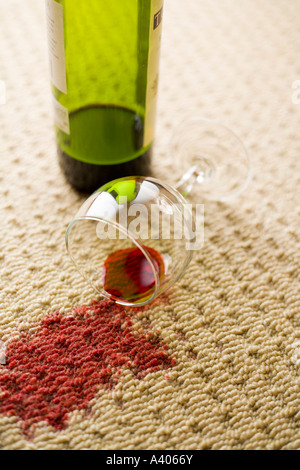 Ribaltato un bicchiere di vino rosso con vino versato su un tappeto di lana Foto Stock