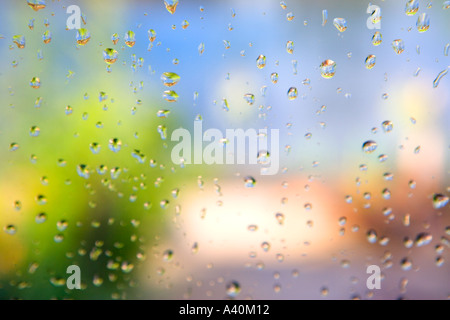 Guardare fuori per un giardino come il sole che appare dopo la pioggia con gocce di pioggia sulla finestra Foto Stock