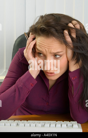 Giovane donna segretario o lavoratore di ufficio cercando interessati e preoccupati per qualcosa che ha visto sul computer Foto Stock