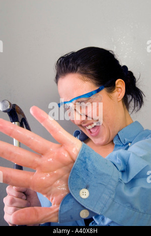 Giovani femmine urtare accidentalmente acqua tubo con unghia mentre effettuare miglioramenti home Foto Stock