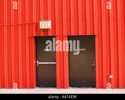 Marrone due porte di metallo in un metallo ondulato edificio con segnale di uscita Foto Stock