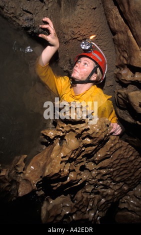 Femmina speleologo strisciando nel flusso stretto passaggio della grotta di Clearwater Borneo Malaysia Foto Stock