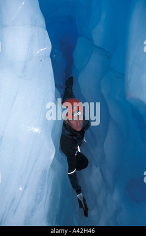 Speleologo spremitura attraverso una stretta caverna di ghiaccio passaggio ghiacciaio Fox Nuova Zelanda Foto Stock