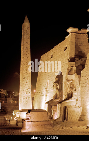 Il magnifico tempio di Luxor al crepuscolo con colossali statue di Ramses II e un obelisco di fronte all'ingresso tralicci Foto Stock