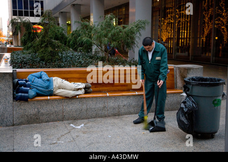 Streetcleaner lavorano intorno all uomo senza tetto dorme sul banco di lavoro Foto Stock