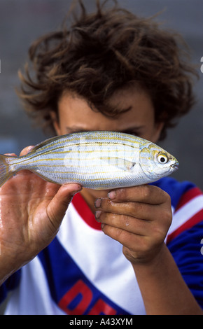 Un giovane ragazzo in possesso di un pesce che ha appena pescato, Palermo, Sicilia, Italia. Foto Stock