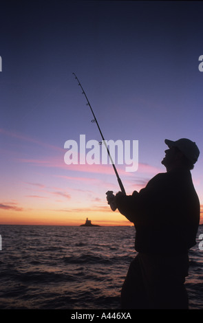 Fisherman la bobinatura di pesce al sorgere del sole su una barca Long Island Sound, Connecticut, Stati Uniti d'America Foto Stock