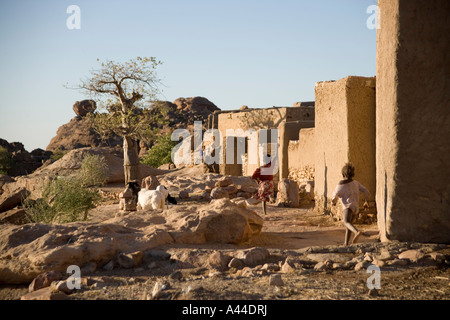 Case del Borgo di Sanga appollaiato sulla scarpata superiore e in esecuzione i bambini ,Paese Dogon del Mali, Africa occidentale Foto Stock