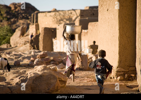 Case del Borgo di Sanga appollaiato sulla scarpata superiore e in esecuzione i bambini ,Paese Dogon del Mali, Africa occidentale Foto Stock