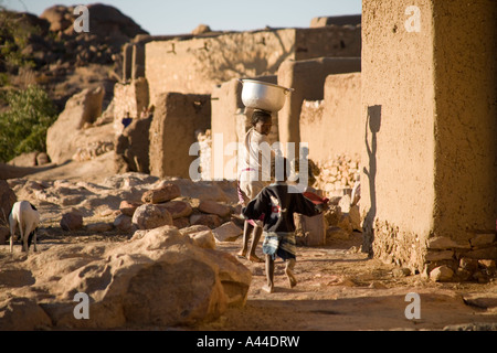 Case del Borgo di Sanga appollaiato sulla scarpata superiore e in esecuzione i bambini ,Paese Dogon del Mali, Africa occidentale Foto Stock