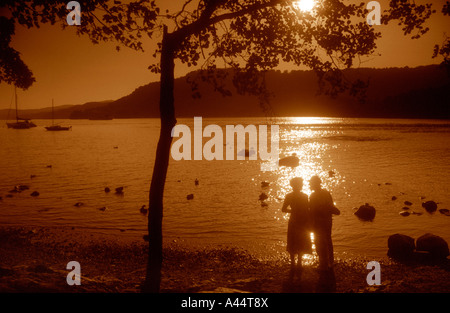 Coppia Matura stagliano contro le acque del lago di Windermere In Cumbria il Lake District. Foto Stock