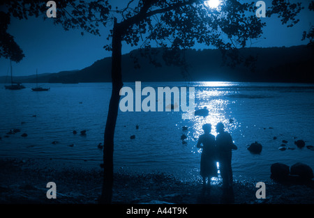 Coppia Matura stagliano contro le acque del lago di Windermere In Cumbria il Lake District. Foto Stock