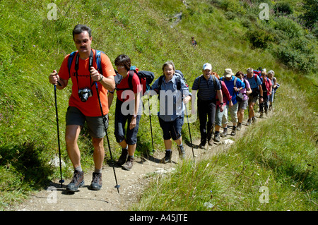 Signor Escursionismo gruppo uno dopo l'altro su un percorso che attraversa un pendio erboso Haute Savoie Francia Foto Stock