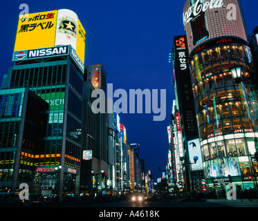 Giappone Honshu Ginza Tokyo di notte vista lungo la strada illuminata con le insegne al neon su department store di edifici Foto Stock