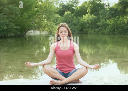 La donna nella posizione del loto accanto all'acqua Foto Stock